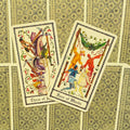 Tarot kortos su atverstomis Trijų lazdų ir Keturių lazdų kortomis, rodomos iš viršaus ant dekoratyvios nugarėlės