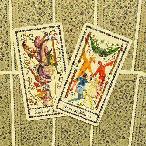 Tarot kortos su atverstomis Trijų lazdų ir Keturių lazdų kortomis, rodomos iš viršaus ant dekoratyvios nugarėlės