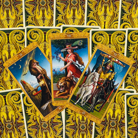 Tarot kortos ornamentiniu auksiniu atspaudu, trimis atmerktomis didžiųjų arkana kortomis centre pasvirusiu kampu