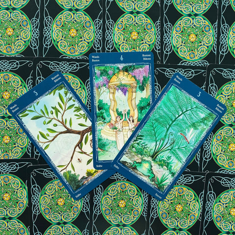 Tarot kortos su mėlynomis kraštinėmis — trys atverstos Bastonų kortos (3, 4, 5) ant žalio celtic rašto