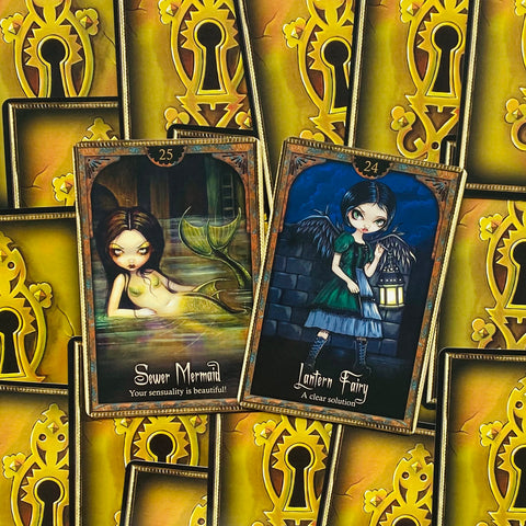 tarot kortos atverstos dvi kortos: žalsva undinė (Sewer Mermaid) ir mėlyna žibintų fėja (Lantern Fairy), su auksinėmis raktų nugarėlėmis