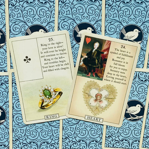 Lenormand kortos, artima dviejų kortų (Ring ir Heart) kompozicija ant mėlyno raštuoto fono, parodytos priekiniu kampu