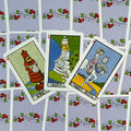 tarot kortos su šviesiai violetiniu gėlėtu nugarėliu, trys išrikiuotos karališkos figūros – karalius, karalienė ir riteris