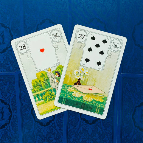 Lenormand kortos su kortelėmis 28 (vyras) ir 27 (laiškas), išdėstytos kampu ant mėlyno ornamentuoto fono