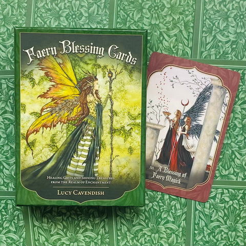 Kortų rinkinys Faery Blessing Lucy Cavendish — žalias dėklas su geltonai‑žalia fėja ir viena atvira korta su raudonu kraštu