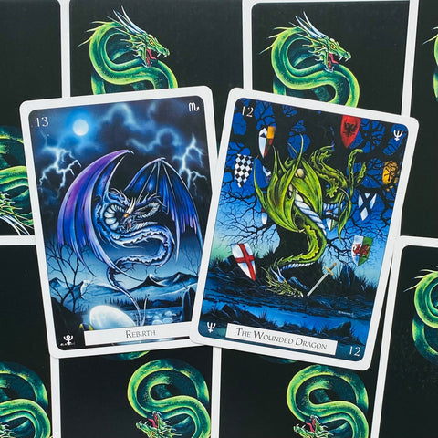Tarot kortos drakonų tematikos: dvi atverstos kortos „Rebirth“ ir „The Wounded Dragon“ ant žalio nugarėlių fono