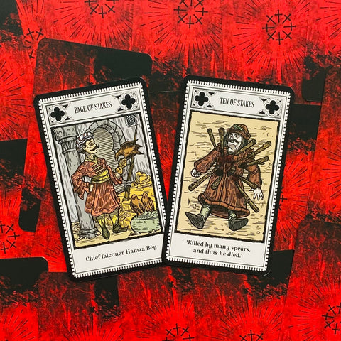 Tarot kortos su atverstu Page of Stakes ir Ten of Stakes motyvais ant raudono nugarėlių fono, detalių iliustracijos