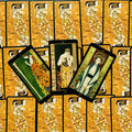 Tarot kortos Klimto stiliaus komplektas, trys skirtingos priekinių kortų iliustracijos fanuotos virš auksinių nugarėlių rašto, detalė parduotuvės galerijai