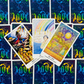 Tarot kortos trijų kortų išdėstymas su spalvingomis iliustracijomis, mėlynu graviruotu fonu ir baltais kraštais