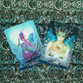 Tarot kortos, dvi atviros kortos (Metamorphosis ir The Protector) ant žaliai dekoruoto fono, matomos priekio iliustracijos