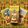 Tarot kortos Ramses geltona dėžutė centre, trys atverstos egiptietiškos kortos ir spalvingas raštuotas galinis fonas