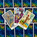 Tarot kortos, fanuotos iš viršaus: trys iliustruotos kortos (Queen, Knight, Page) ant mėlyno‑žalsvų holografinių nugarėlių