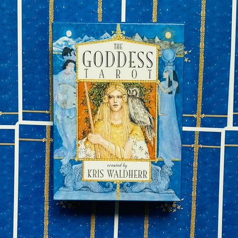 Tarot kortos The Goddess dėžutėje, mėlynoje su aukso akcentais ant žvaigždėto fono, viršutinė priekinė pusė, aut. Kris Waldherr