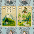 Lenormand kortos, dvi atverstos: 21 Kalnas ir 22 Kryžkelė, artimas planas ant mėlyno ornamentuoto fono