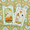 Tarot kortos su egiptietišku dizainu, dvi atvertos didžiosios arkana kortos ant raštuoto žalių kortų galinių pusių fono