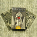 Oracular kortos Old Cartomancy dėžutė centre, klasikinis nespalvotas dizainas su ryškia raudona širdimi ir dvi išskleistos kortos fone