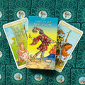 Tarot kortos "New Vision" pilnas denis su dėkle centre, dvi išverstinės kortos šonuose ir žalio rašto nugarėlės fone