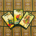 Tarot kortos su ornamentiniu auksiniu gale, trys atverstos kortos (Consolation, Surprise, Fortune) su žaliais kraštais