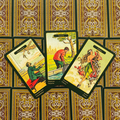 Tarot kortos su ornamentiniu auksiniu gale, trys atverstos kortos (Consolation, Surprise, Fortune) su žaliais kraštais