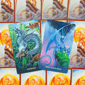 tarot kortos su dviem atverstais variantais — žaliai mėlyna „Patience“ ir violetinė „Open Your Mind“, ryškios oranžinės nugarėlės