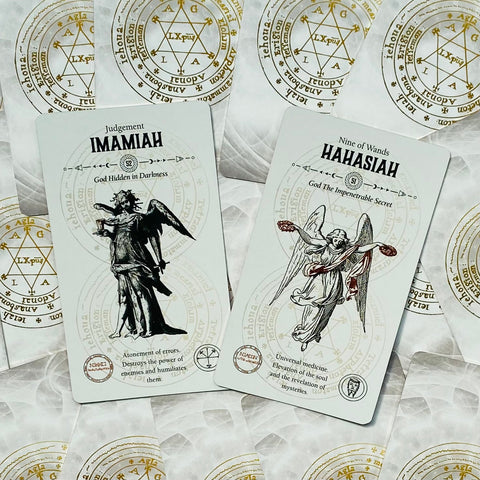 tarot kortos baltame fone su auksiniais sigilais, dvi kortos (Imamiah ir Hahasiah) matomos iš viršaus