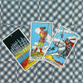 tarot kortos Rider–Waite trijų kortų išklotinė: centre Page of Swords, dešinėje Knight of Swords, šviesiai mėlynas raštuotas fonas