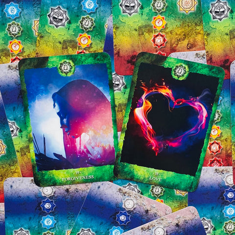 Tarot kortos su žaliu rėmeliu, paskleistos ant čakrų raštuoto fono — matomos atviros Atleidimas ir Meilė kortos