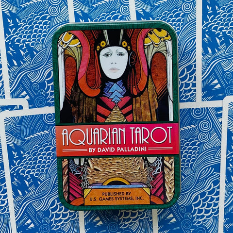 Aquarian Tarot metalinė dėžutė su David Palladini viršeliu, ryškiais raštais ir mėlynu kortų fono ornamentu