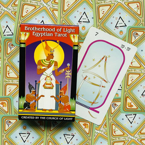 Taro kortų rinkinys Brotherhood of Light su ryškia egiptietiška dėže ir atversta 7 korta ant raštuoto fono