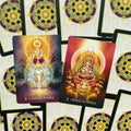 Tarot kortos ryškiomis auksinėmis ir violetinėmis iliustracijomis; dvi kortos (Ashuku Nyorai, Dainichi Nyorai) iš viršaus, matomas ornamentuotas nugarėlis
