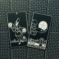 tarot kortos juodai baltos Rider‑Waite stiliaus, dvi kortos (Dviejų pentaklių ir Pentaklių tūzas) ant raštuotos nugarėlės