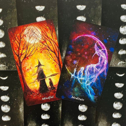 Tarot kortos dvispalvės, Mindful (rausvai‑oranžinė raganos scena) ir Meditate (mėlyna–violetinė), išdėstytos ant mėnulio fazių nugarėlių