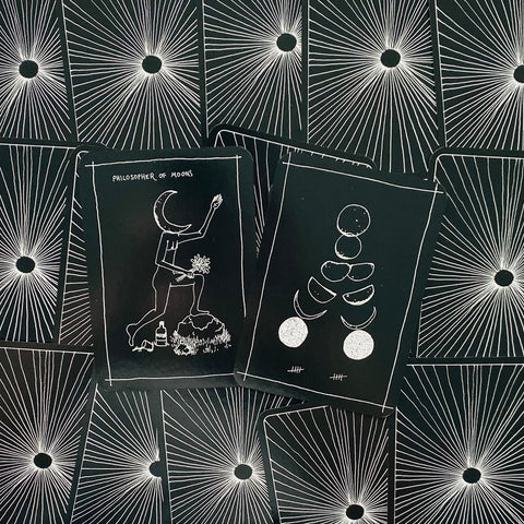 Tarot kortos juodos baltos mėnulio iliustracijos, dvi išklotos kortos, rodančios unikalų priekį ir nugarėlės dizainą