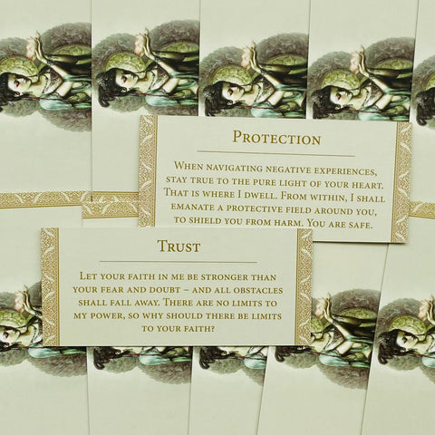 Orakulo kortelės, artimas horizontalus išdėstymas su kreminėmis aukso rėmelio kortelėmis ir pavyzdiniais Protection bei Trust tekstais, demonstruoja kortelių meninį dizainą