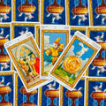 tarot kortos katėmis, trijų kortų išklotinė su aukso rėmais ant mėlyno nugarėlių rašto, fotografuota iš viršaus