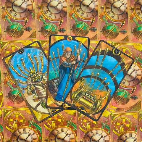 Tarot kortos steampunk stiliaus, trimis atverstos kortos (9,10,8) su auksinėmis detalėmis ir laikrodžių mechanikos fonu
