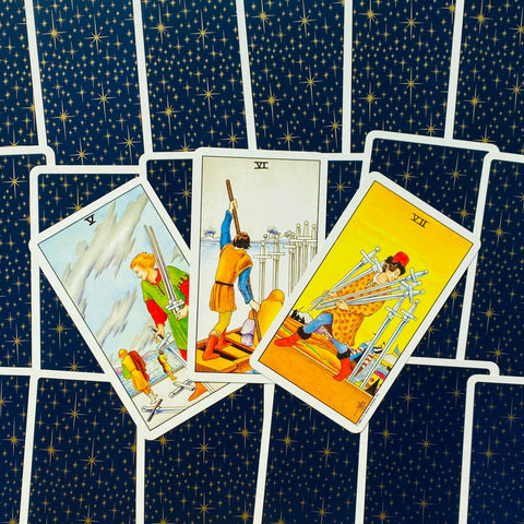 Tarot kortos Rider–Waite stiliaus, tamsiai mėlyna žvaigždėta nugarėlė, trijų kortų išdėstymas (V, VI, VII) rodantis konfliktą ir pergalę