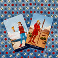 Tarot kortos — Page of Cups ir Page of Wands ant mėlynos gėlių drobės, priekinis artimas planas, ryškios spalvos