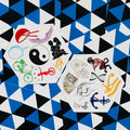 Laikiniai tatuiruočių lipdukai — du šešiakampiai lapeliai su įvairiais simboliais (yin‑yang, tarot, inkaras, dviratis) ant mėlyno‑juodo trikampio fono