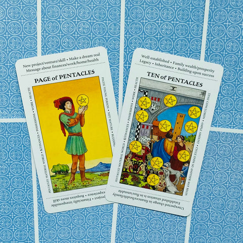 Tarot kortos Rider–Waite tipo atvertos: Page of Pentacles ir Ten of Pentacles su ryškiais geltonais motyvais ant mėlyno ornamentuoto fono