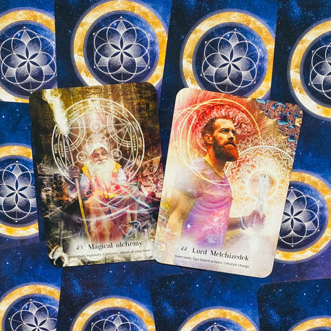 kortos orakulinės, dvi atverstos kortos (Magical Alchemy, Lord Melchizedek) ant mėlyno žvaigždėto fono, artimas kampas