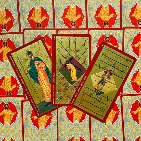 Tarot kortos, auksinio ir raudono dizaino Bastonų kortų trio (9, 10 ir riteris), išdėstyti ant ornamentuotų nugarėlių