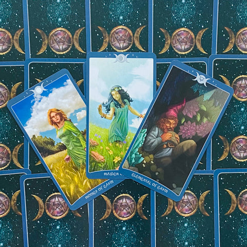 Tarot kortos trijų kortų išdėstyme, mėlyti rėmeliai ir ryškūs žemės motyvai su tamsia žvaigždėta nugarėle