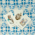 Tarot kortos — trys atverstos taurės (Five, Four, Three of Cups) ant mėlyno akvarelinio mozaikinio fono, pabrėžtas kortų iliustracijų dizainas