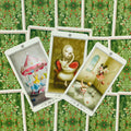 Tarot kortos su meniškais pasakiškais piešiniais — trys atvertos kortos centre ant žalios uogomis raštuotos nugarėlės, rodoma priekio variacija