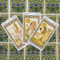 Tarot kortos su Art Nouveau iliustracijomis — trys atverstos kortos ant ornamentuotų nugarėlių, matomos iš viršaus