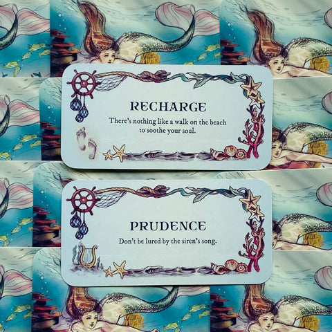 Orakulo kortos su undine: dvi baltos kortos (Recharge, Prudence) ant mėlyno jūrinio fono, rėmai su žuvimis ir kriauklėmis
