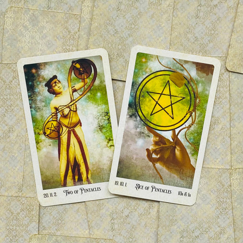 Tarot kortos Pentaklų rinkinys: Ace ir Two of Pentacles, geltoni penkiakampiai simboliai, nuotrauka iš viršaus ant raštuoto fono