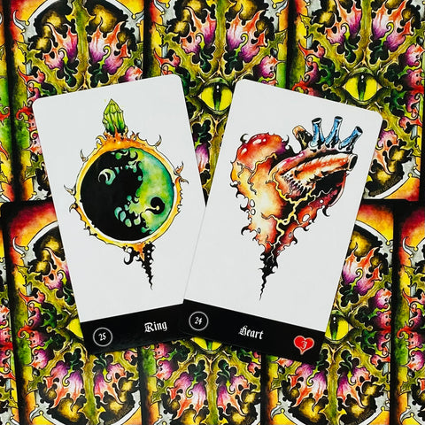 Tarot kortos su akvarelinėmis iliustracijomis: dvi atverstos baltos kortos — Žiedas ir Širdis — ant spalvoto nugarėlių fono