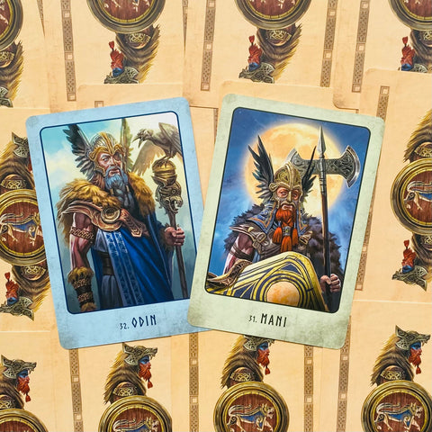 Tarot kortos su nordiškų dievų iliustracijomis — dvi atverstos kortos (Odin ir Mani) ant raštuoto nugarėlių fono